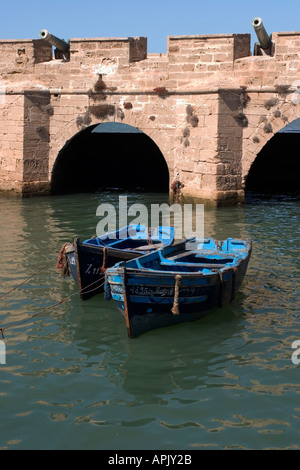 Zwei kleine blaue Sardine Boote im Hafen von Essaouira mit der Wand und zwei kleinen portugiesischen Kanonen im Hintergrund Stockfoto