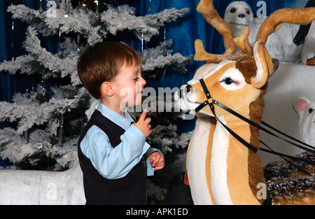 kleiner Junge spielt in Santas Grotte zu Weihnachten Stockfoto