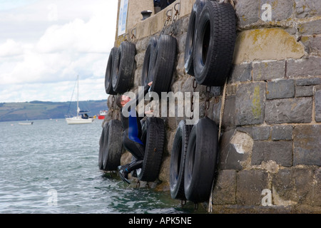 Mann klettert der Hafenmauer in Tenby, Wales Stockfoto