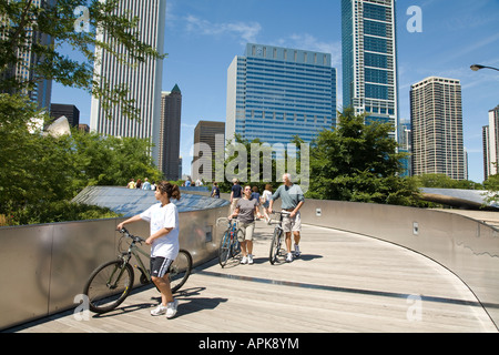 ILLINOIS-Chicago-Männer und Frauen wandern Fahrräder auf BP Brücke im Millennium Park geschwungenen Metallstruktur Hochhäuser Stockfoto