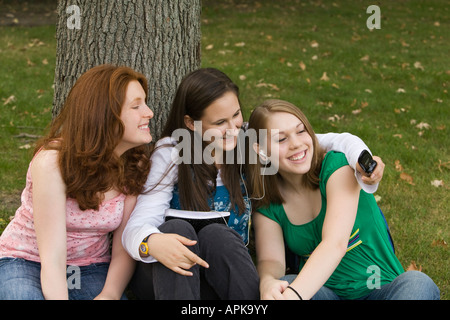 ILLINOIS Riverwoods drei Mädchen im Teenageralter mit eigenen fotografieren mit Handy draußen zu sitzen, Gras Stockfoto