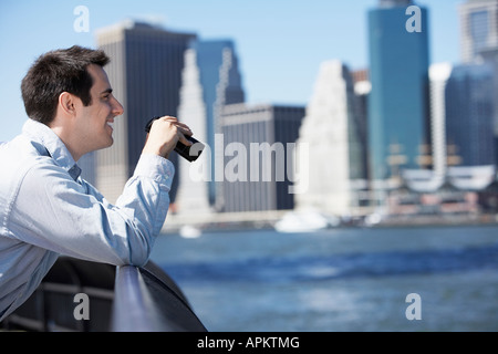 Mann mit Fernglas, Manhattan im Hintergrund, New York City, New York, USA Stockfoto