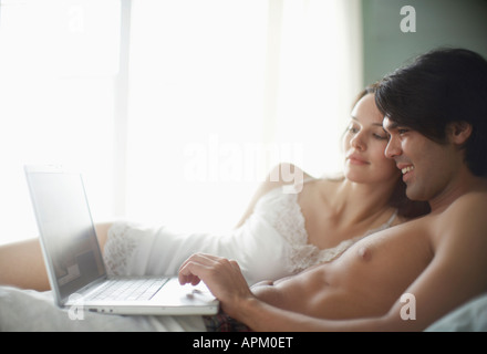 Junges Paar mit Laptop-Computer auf Bett Stockfoto