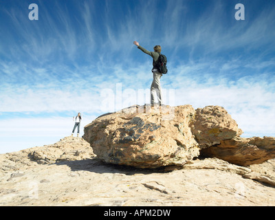 Mann und Frau stehen auf Felsbrocken und winken einander Stockfoto