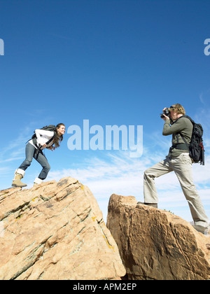 Menschen machen Fotos von Frau auf Felsbrocken, Low Angle View Stockfoto