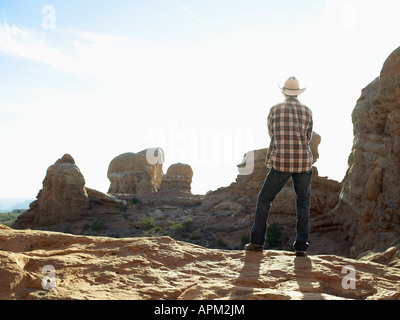 Junger Mann in Cowboy Hut steht auf einer Klippe, Rückansicht Stockfoto