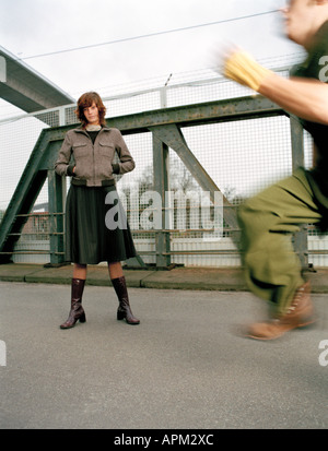 Frau stehend auf Brücke, Mann läuft Stockfoto