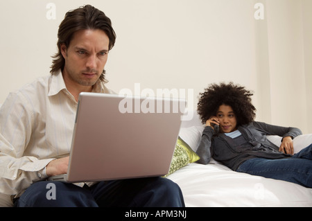 Junger Mann mit Laptop und Frau am Telefon sprechen Stockfoto
