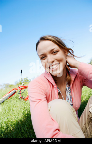 Junge Frau sitzt auf der Wiese, im Hintergrund (Hochformat) Stockfoto