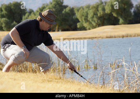 Der Mensch auf der Suche nach Golf Ball im Teich Stockfoto