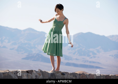 Frau in Kleid zu Fuß auf stein Wand Stockfoto