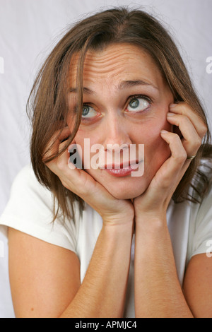 Gorgeous young brunette woman with nervous apprehensive anxious bothered concerned edgy facial expression holds face in hands Stockfoto