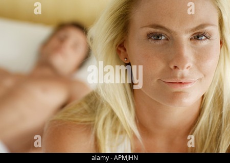Blonde junge Frau mit Mann liegend auf Bett im Hintergrund Stockfoto