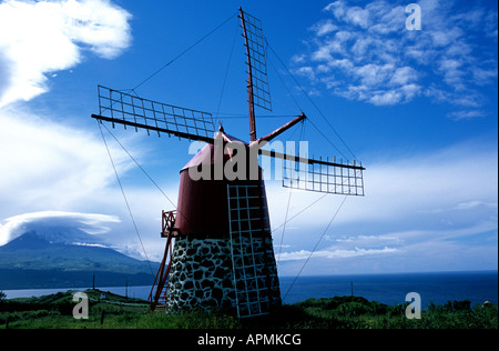 Ein Azoren Windmühle auf der Insel Faial; benachbarten Pico Insel seiner bergigen Gipfel in der Ferne sehen und Stockfoto