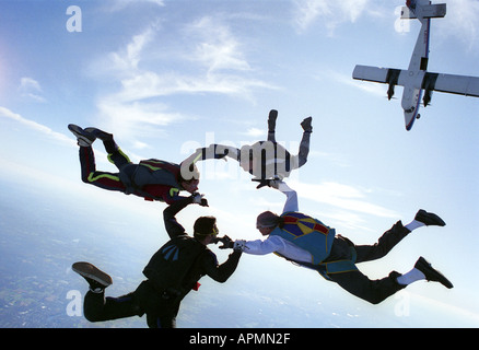 Vier Fallschirmspringer im freien Fall Hand in Hand Stockfoto