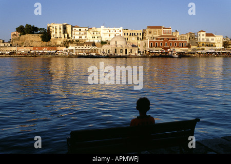 Sitzende Junge Blick über Chania Hafen am späten Nachmittag Stockfoto
