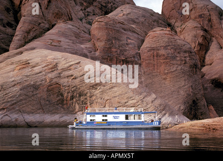 Ein Hausboot ankert in einer Bucht, umgeben von hoch aufragenden Sandsteinfelsen am Lake Powell Stockfoto