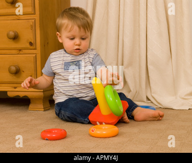 Baby Junge elf Monate alt, der mit abgestuften Ringen spielt Stockfoto