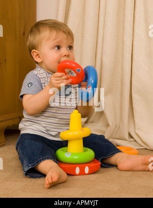 Baby Junge elf Monate alt spielt mit benotet Ringe Stockfoto