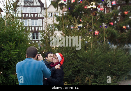 Der Mann, der ein Bild von einem jungen Paar auf dem Weihnachtsbaummarkt in Straßburg, im Elsaß, in Frankreich und in Europa machte Stockfoto