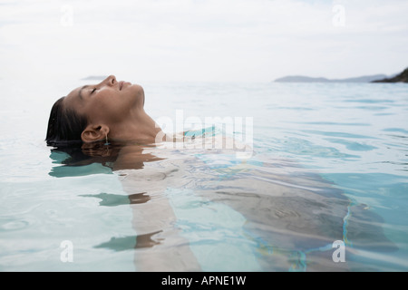 Junge Frau, die im Wasser schwimmen Stockfoto