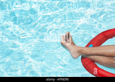 Der Mann Beine auf aufblasbaren Matratze im Schwimmbad Stockfoto