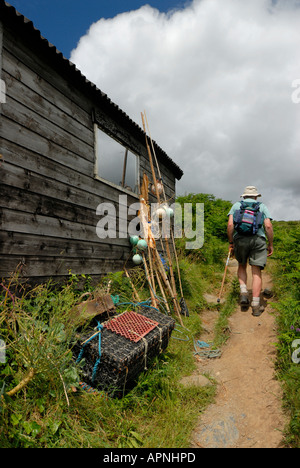 Fischer Hütte in Prussia Cove Prussia Cove Cornwall England mit Angeln Utensilien und ein Mann zu Fuß den Küstenpfad Stockfoto