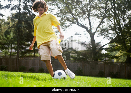 Junge (12-13) das Spiel mit dem Fußball Stockfoto