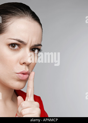 Junge Frau mit Finger auf die Lippen Stockfoto