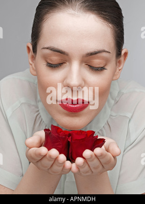 Junge Frau riecht rote Rosen Stockfoto