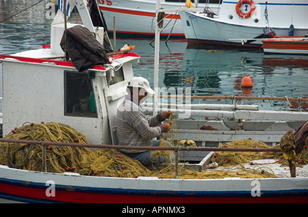 Ein Fischer arbeitet auf seine Netze auf einem traditionellen kleinen griechischen Fischerboot Stockfoto