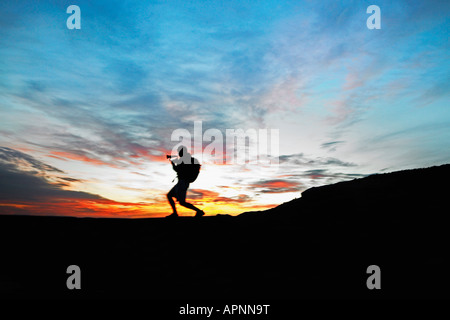 Männliche Wanderer spielen Horn auf dem Dach bei Sonnenuntergang Stockfoto