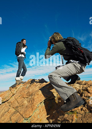 Menschen machen Fotos von Frau auf Felsbrocken Stockfoto