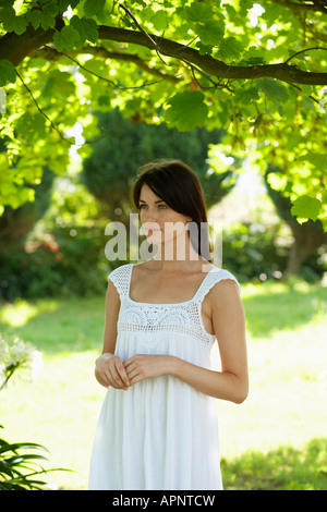 Junge Frau in weißem Kleid im Garten Stockfoto