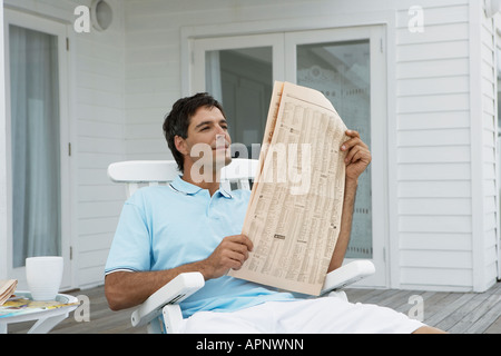 Mitte der erwachsene Mann lesen Zeitung auf der Veranda Stockfoto