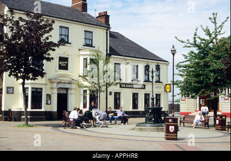 Menschen ruht auf den Bänken auf dem Marktplatz außerhalb der Sir John Warren Gastwirtschaft und Hotel A kleine Gusseisen Brunnen Formen das Quadrat s Herzstück Ilkeston Stockfoto