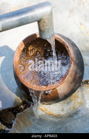 Füllen einen Tontopf mit Wasser bei einer Handpumpe in der indischen Landschaft. Andhra Pradesh. Indien Stockfoto