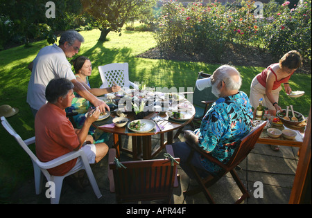 Eine Gruppe von Freunden mit Abendessen in einem englischen Country Garden in Großbritannien Stockfoto
