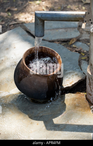 Füllen einen Tontopf mit Wasser bei einer Handpumpe in der indischen Landschaft. Andhra Pradesh. Indien Stockfoto