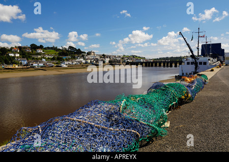 Fischernetze am Kai in Bideford Hafen. Das 13. Jahrhundert Bideford lange Brücke in der Ferne erstreckt sich über den Fluss Torridge nach Osten - - Wasser. Die Lundy Fähre, MS Oldenburg, können gesehen werden entlang der Kai. Devon. Stockfoto