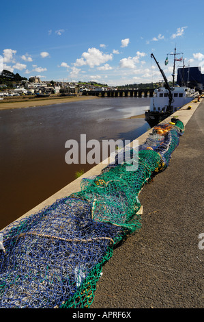 Fischernetze am Kai in Bideford Hafen. Das 13. Jahrhundert Bideford lange Brücke in der Ferne erstreckt sich über den Fluss Torridge nach Osten - - Wasser. Die Lundy Fähre, MS Oldenburg, können gesehen werden entlang der Kai. Devon. Stockfoto