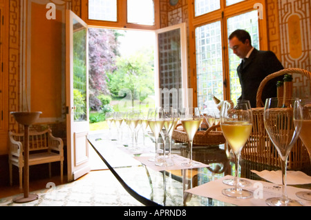 In der Verkostung Zimmer einen Kellner gießt Champagner für eine Weinprobe. Champagner-Gläser in einer Zeile mit einen Blick auf den Garten hinter dem Haus bei Champagne Deutz in Ay, Vallée De La Marne, Champagner, Marne, Ardennen, Frankreich, niedrige leicht körnig Korn Stockfoto