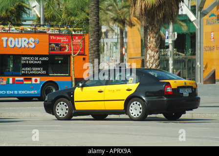 Seitenansicht des ikonischen gelben und schwarzen spanischen Taxi & Fahrer vorbei an einem offenen Barcelona Sightseeing Tour Bus in der Straßenszene Katalonien Spanien EU Stockfoto