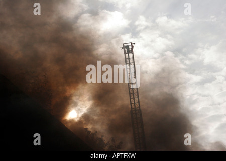 Eine Leiter verlängert über den Rauch aus einem Hausbrand Struktur immer bereit, Pumpe Wasser auf das Feuer Stockfoto