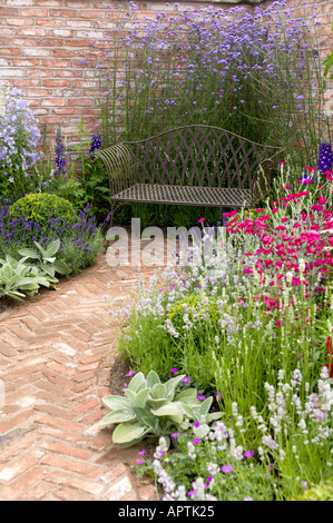 Flower Show Fischgräten Ziegel Gartenweg mit Eisenbank Stockfoto
