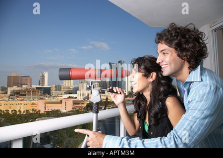Hispanische paar Blick durch das Teleskop auf dem Balkon Stockfoto