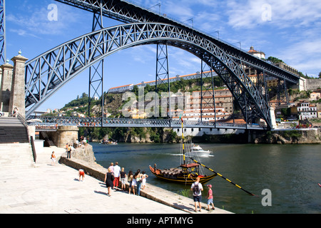 Touristen und einheimische Sonnenbaden am Douro-Fluss-Ufer in der Nähe von D. Luiz ich Brücke in Porto, Portugal. UNESCO-Welterbe. Stockfoto