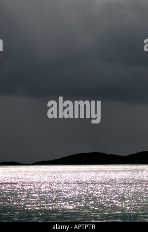 Sturmwolken Sonnenlicht auf dem Wasser St. John US Jungferninseln | St. JOHN, U.S. Jungferninseln – Sonnenlicht bricht durch dunkle Sturmwolken über der Karibik in der Nähe von Galgen Point und bildet eine Silhouette eines niedrigen Inselrückens am Horizont. Die Regenzeit von St. John verläuft normalerweise von September bis November, und die vulkanischen Hügel aus der Kreidezeit, die heute von subtropischen Trockenwäldern bedeckt sind, erheben sich stark aus dem umliegenden Wasser. Stockfoto
