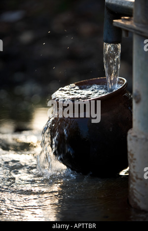 Füllen eine indische Tontopf mit sauberem Süßwasser eine Handpumpe Wasser in der indischen Landschaft. Andhra Pradesh, Indien Stockfoto