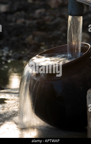 Füllen eine indische Tontopf mit sauberem Süßwasser eine Handpumpe Wasser in der indischen Landschaft. Andhra Pradesh, Indien Stockfoto